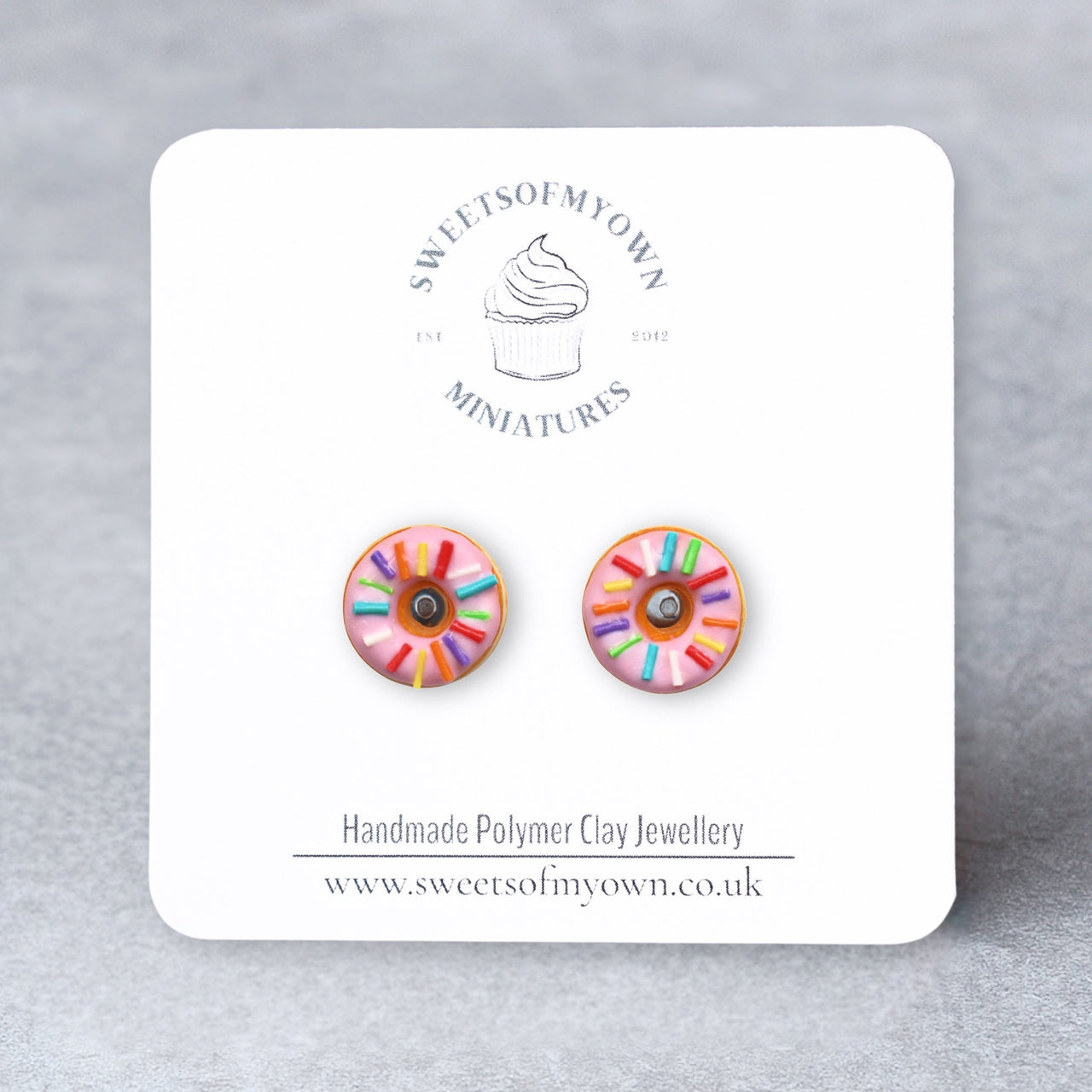 Pink Doughnuts with Rainbow Sprinkles Stud Earrings on a Branded SweetsOfMyOwn Backing Card with a Grey Background