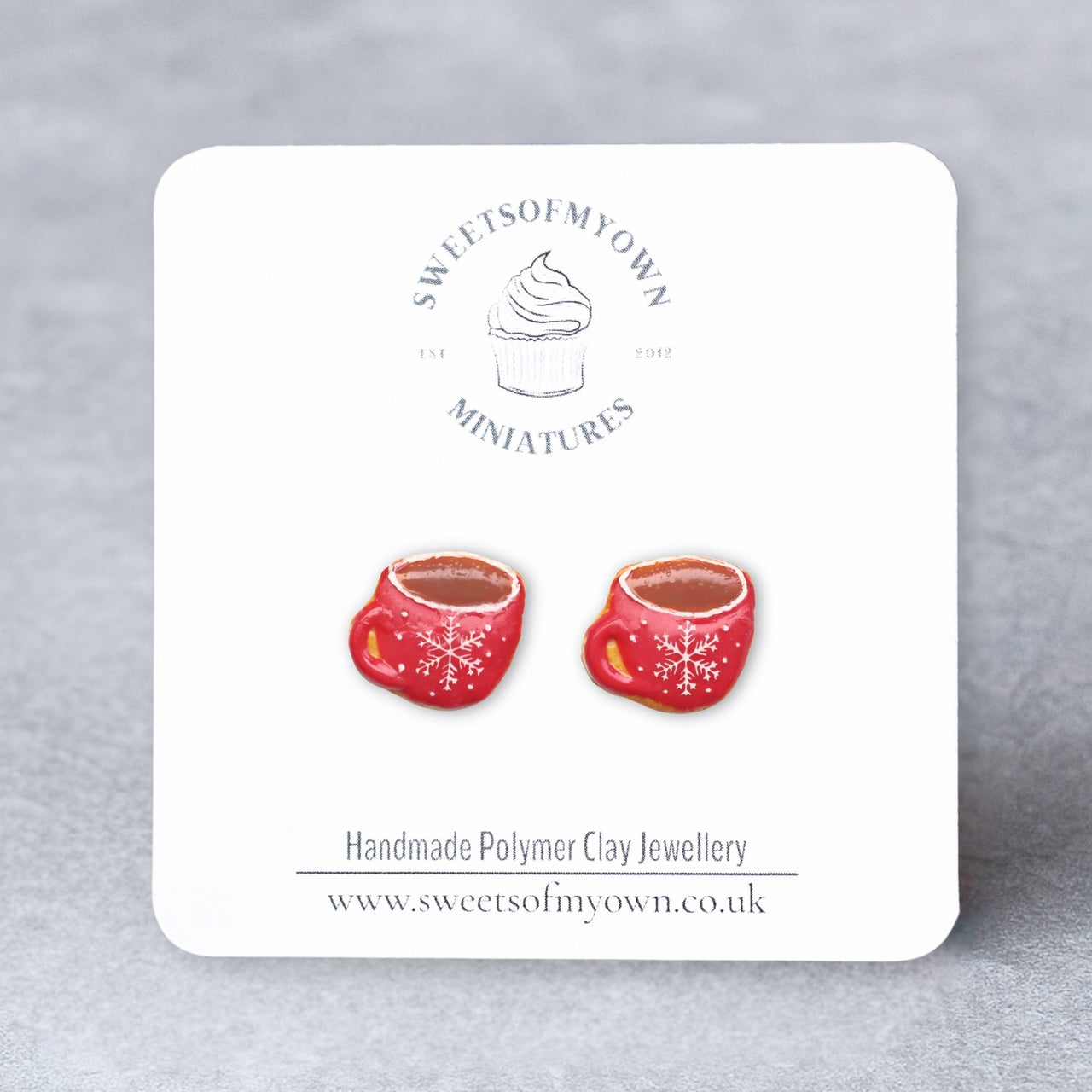 Red Coffee Cups Stud Earrings with a white snowflake design that is on a SweetsOfMyOwn backing card.